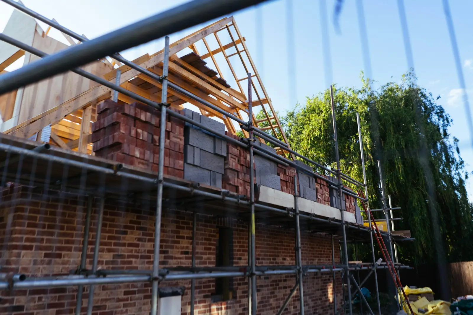 Brick house under construction with scaffolding and roof timbers
