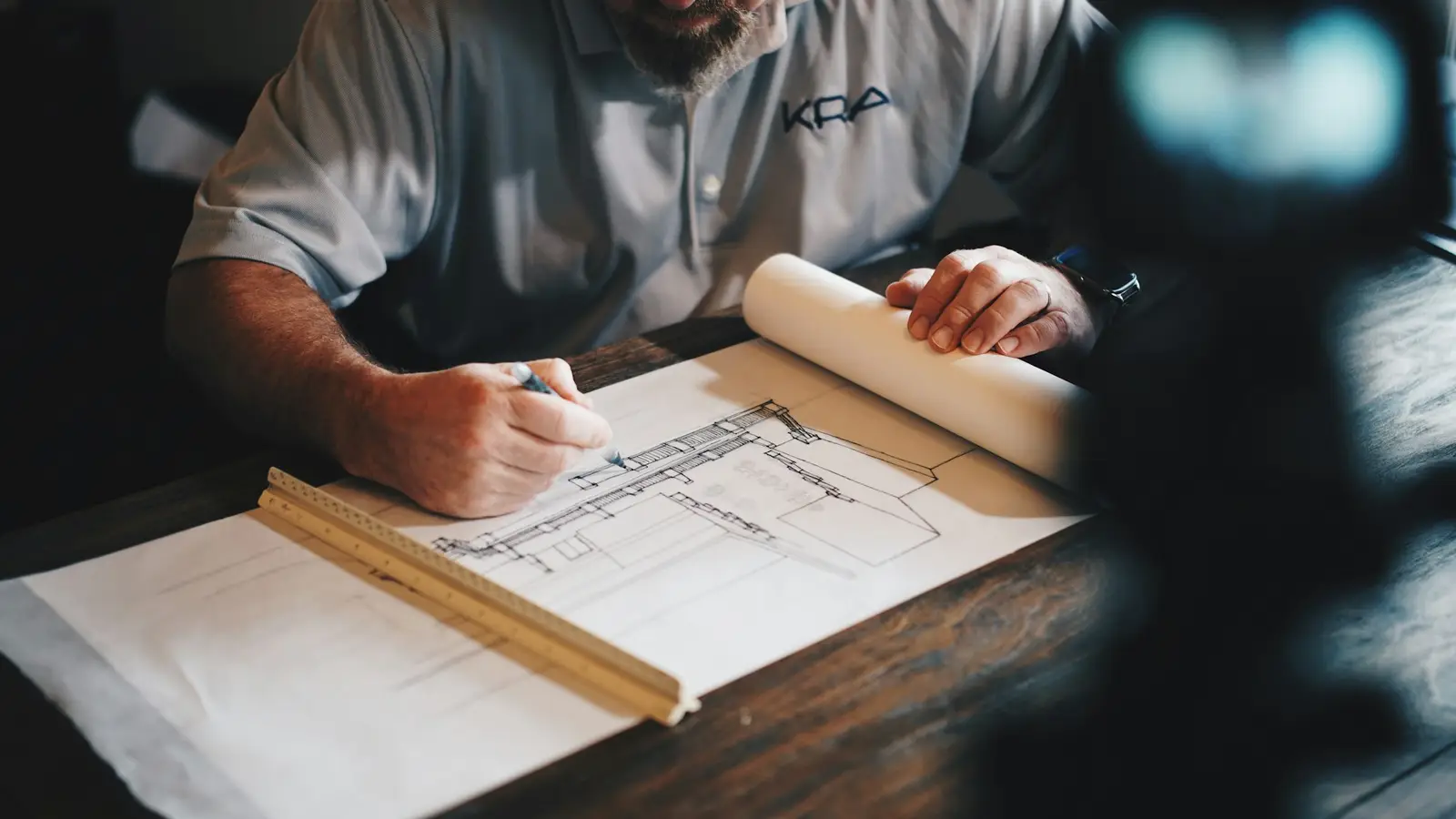 Architect marking up a set of printed building plans at a drawing table