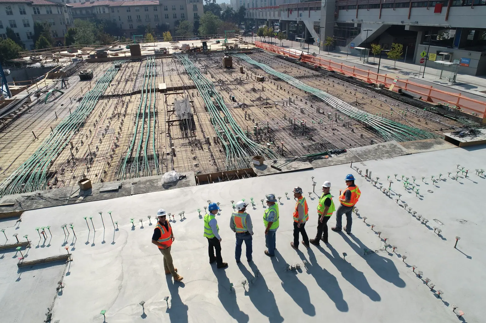 Project team inspecting a large concrete floor slab, with reinforcement laid out for the next pour