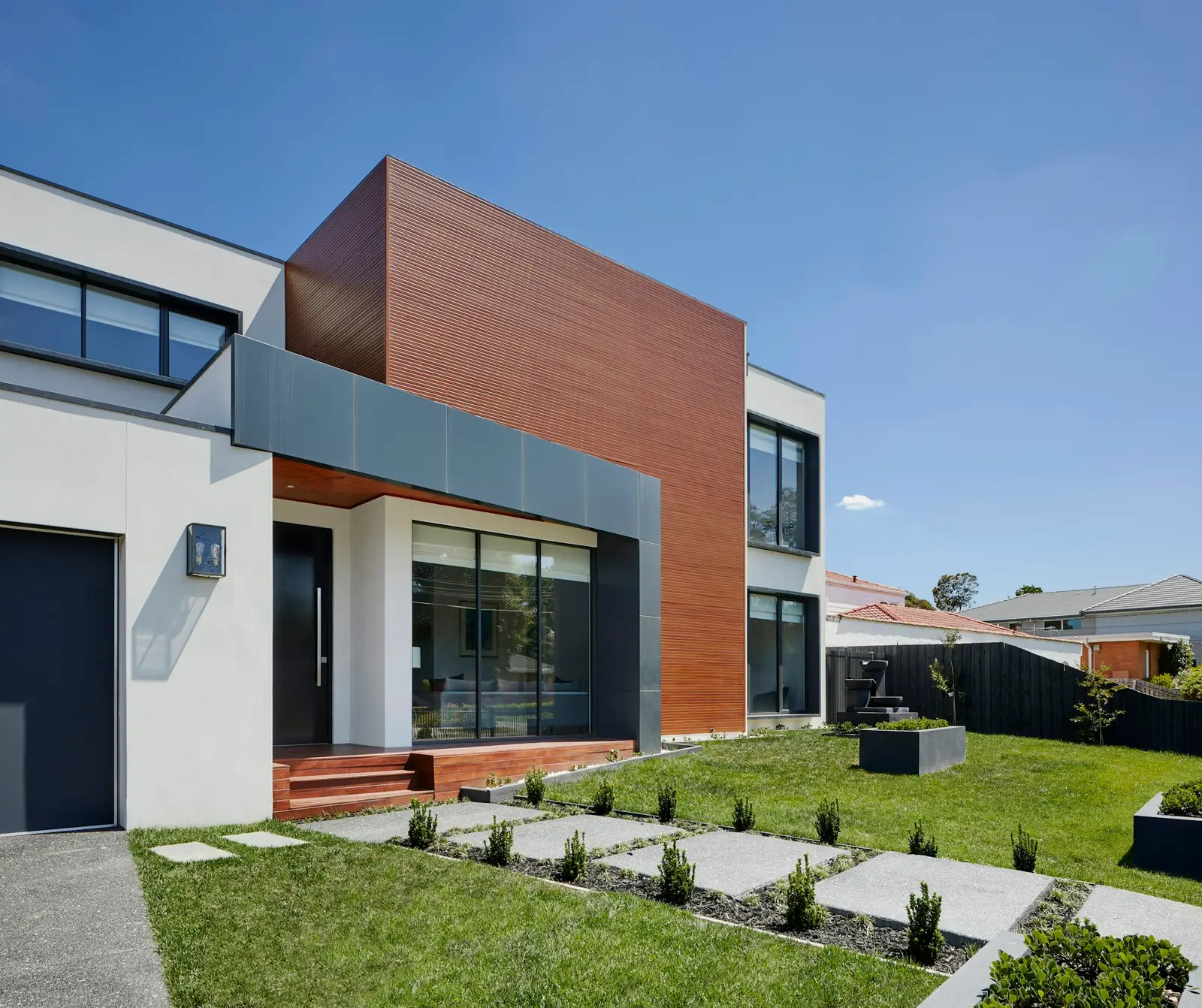 House facade combining render, timber cladding and dark window frames