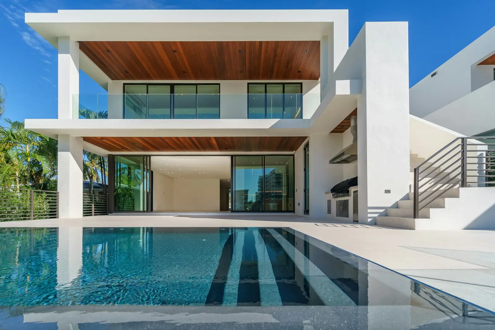 Two-storey concrete house with timber soffits overlooking a swimming pool